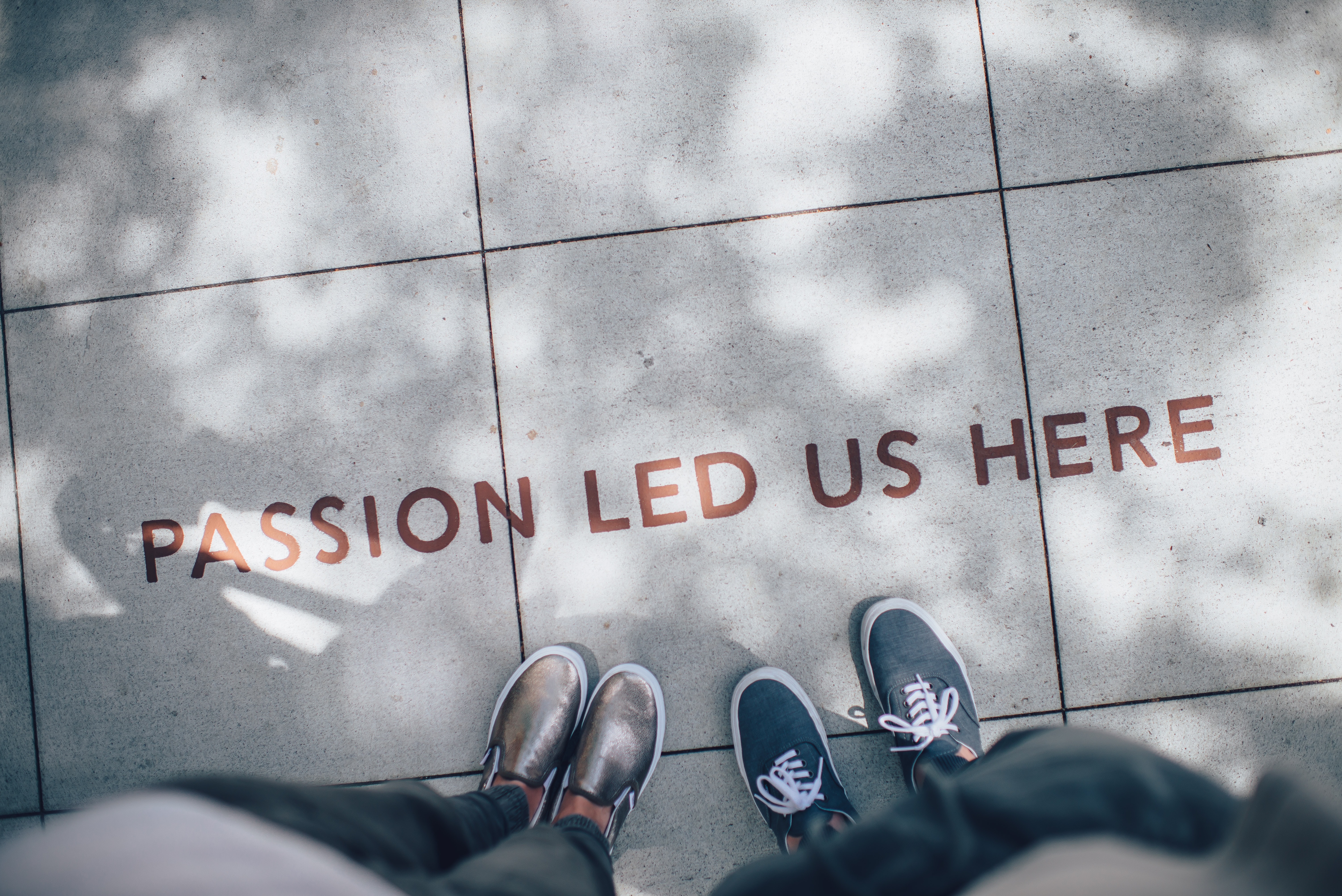 Two pairs of feet visible in front of a sign on the floor saying passion led us here.