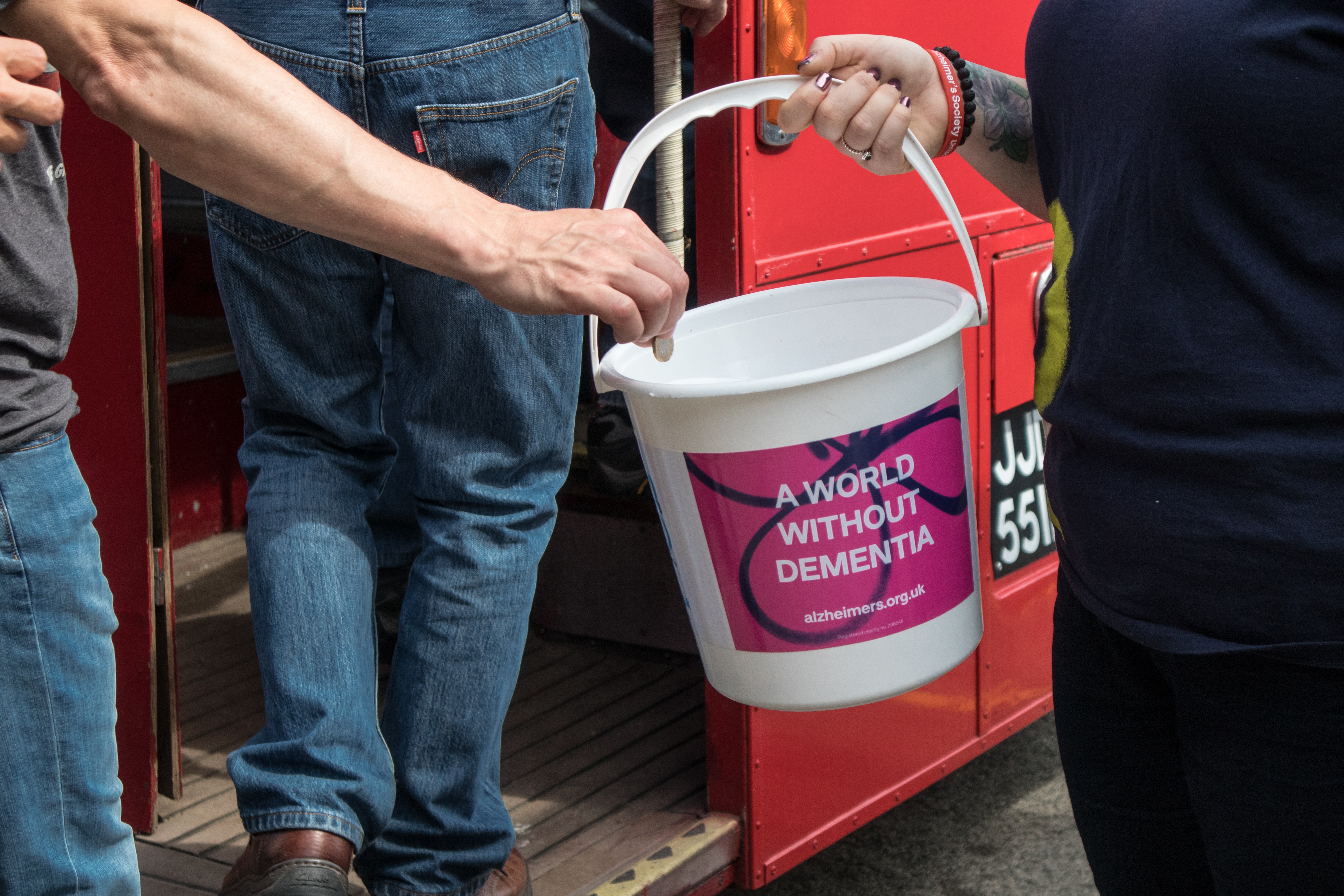 An individual putting money into a fundraising collection bucket