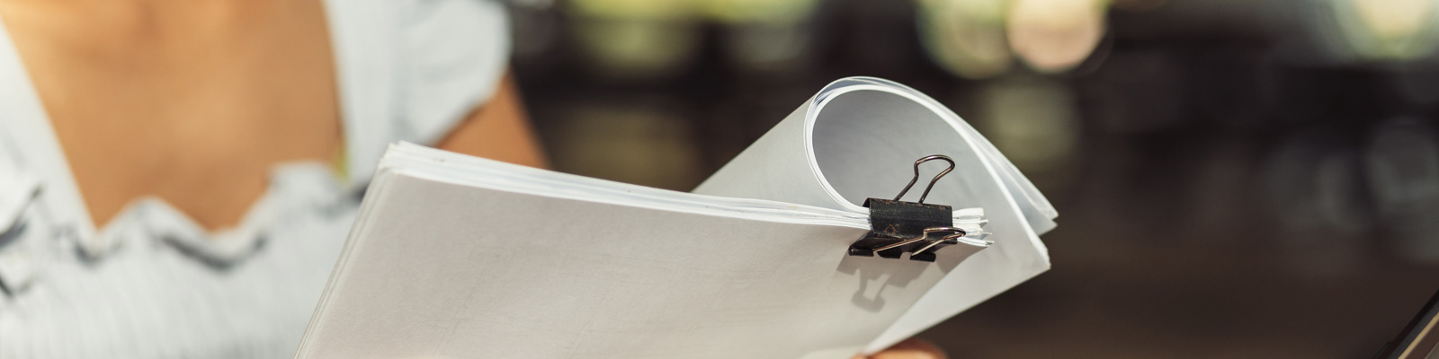 woman opening and reading a paper sheet near laptop on wooden table.
